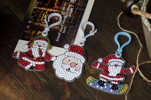DIY Christmas diamond art keychains with Santa Claus designs on a rustic wooden table