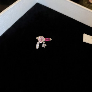 Macro detail of silver heart pistol earring with pink and red gemstones on black velvet