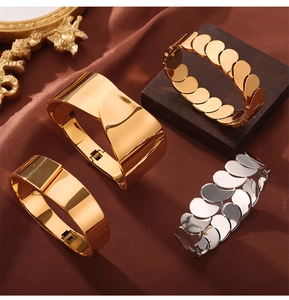 Detailed view of layered geometric water drop bangles and metal chain bracelets in gold and silver