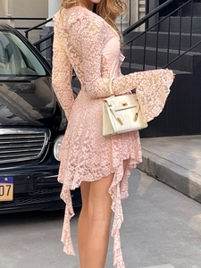 Détail d'une robe en dentelle rose avec manches longues et ourlet irrégulier sur la ville