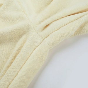 Dettaglio della trama in maglia color crema e cuciture precise dei pantaloni larghi