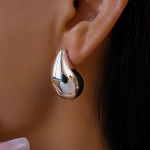 Close-up of minimalist teardrop earrings with a high-polish mirror finish on ear