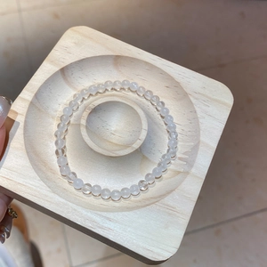 Macro shot of translucent white crystal beaded bracelet on a round wooden display stand