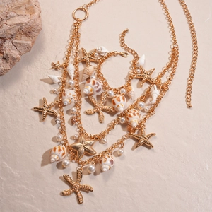 Detailed close-up of golden layered beach chain with starfish, shell and pearl charms