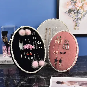 Three-piece oval velvet jewelry display board set with pearl trim and various earrings