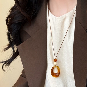 Detailed close-up of the vintage amber-colored drop pendant on a brown cord necklace