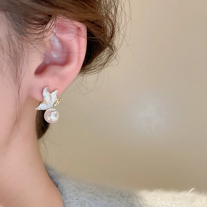 Detailed view of elegant gold butterfly earrings with a white round pearl pendant on model