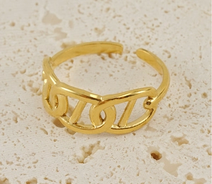 Macro shot of 18K gold plated hollow link ring on a textured beige stone background