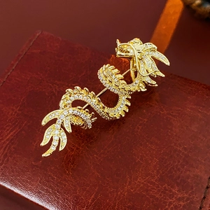 Macro shot of gold dragon brooch with white rhinestones on brown leather background