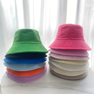 Solid color terry cloth bucket hats in various vibrant colors stacked on a white surface