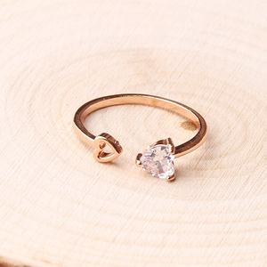 Detail of rose gold heart ring with zircon inlay and open design on wood background