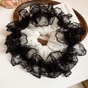 Gros plan d'un chouchou en dentelle vintage à pois noirs et détails de maille sur plateau