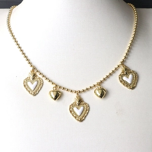 Detail of gold beaded chain necklace with five alternating white enamel heart pendants