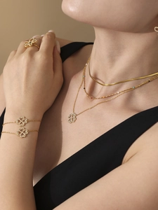 Close-up of golden clover jewelry set with multilayer necklace and zircon bracelet