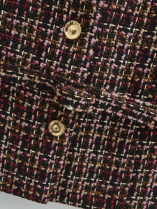Detail of pink and black tweed fabric texture with decorative gold dome metal button