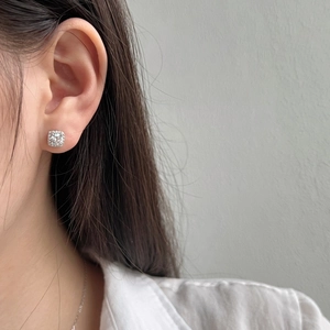 Close-up of square halo silver stud earrings with zircon inlay worn by a female model