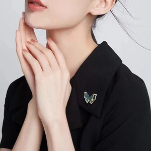 Detailed close-up of a butterfly brooch with blue zircon inlay on a black sweater