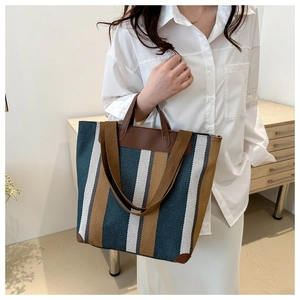 Detail view of the large capacity striped canvas tote bag with brown leather handles