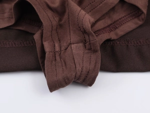 Gros plan d'une couture à double aiguille sur tissu tricoté marron et détails plissés