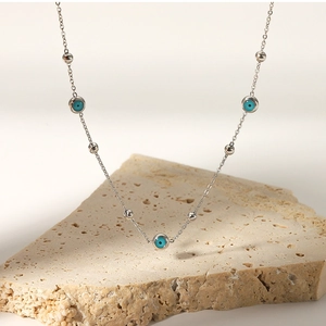 Detail of silver chain necklace featuring blue evil eye charms and small silver beads