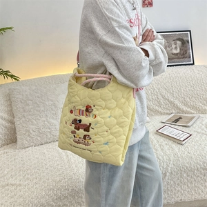 Detail of yellow quilted tote bag with cute cartoon dog embroidery and text on strap