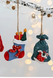 Detail of resin Christmas sock and green bag ornaments hanging on a festive branch
