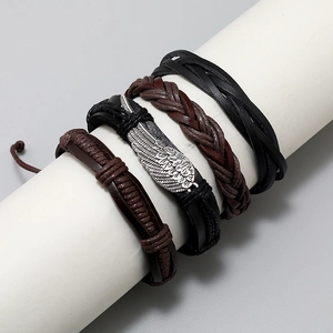 Close-up of four-piece woven leather bracelet set with wing charm on display stand