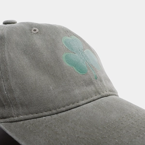 Dettaglio del cappellino grigio vintage lavato con trifoglio verde e cuciture di precisione