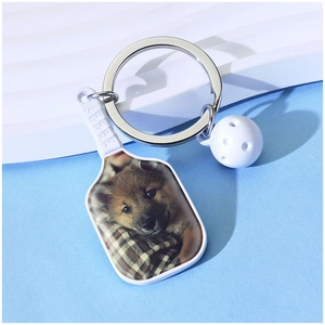 Custom pickleball racket keychain with puppy photo and white ball charm on blue background