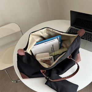 Large black Oxford tote bag with brown leather handles and inner pouch on white table