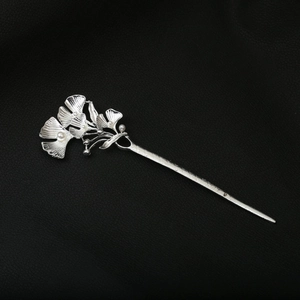 Close-up of silver hair pin with ginkgo leaf design and white pearls on leather