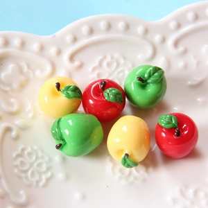Macro shot of colorful resin apple DIY charms on a white ceramic plate accessory