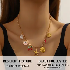 Detail of gold paperclip chain necklace with cherry, heart, and evil eye charms on model