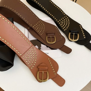 Macro detail of three retro leather belts with vintage gold studs in black and brown tones