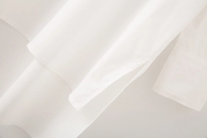 Close-up of white cotton poplin shirt featuring side slit detail and neat stitching