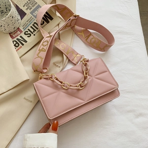 Detail of pink crossbody bag with geometric quilting and wide decorative strap