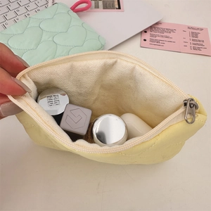 Detail of yellow quilted heart pouch showing interior space for lipstick and cosmetics