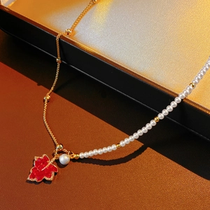 Détail du collier asymétrique plaqué or 18K avec feuille d'érable rouge et perles