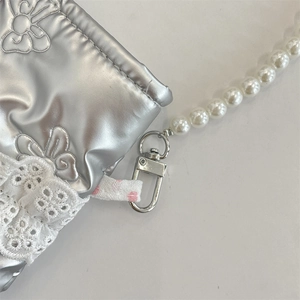 Dettaglio della borsa trapuntata argento con ricami floreali, pizzo e catena di perle