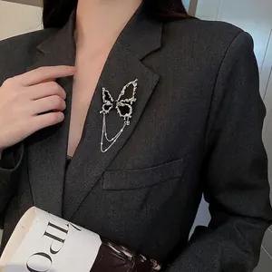 Broche papillon argentée avec incrustation noire et chaînette sur un revers de veste