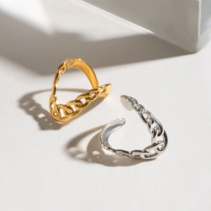Macro detail of adjustable link chain rings in polished gold and silver stainless steel