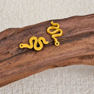 Detail view of two golden snake pendants on wood for DIY jewelry making and craft