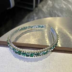Detailed shot of Baroque crystal headband with green rhinestones on display stand