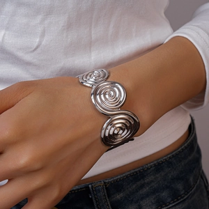 Close-up of a silver spiral geometric cuff bracelet worn on a woman's wrist