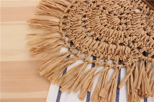 Close-up of bohemian circular straw bag with spiral weaving and long tassel details