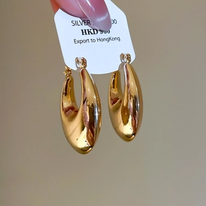 Detail showing polished gold water drop hoop earrings with a high-shine mirror finish