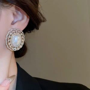 Close-up of vintage French gold stud earrings with large white pearl and zircon ring