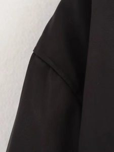 Détail du tissu sergé noir de haute qualité avec des coutures précises sur la veste