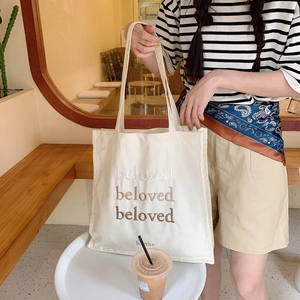 Détail de la broderie beloved sur la surface du sac cabas en toile blanc cassé