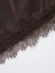 Macro shot of dark brown satin fabric with delicate eyelash lace detailing on edge